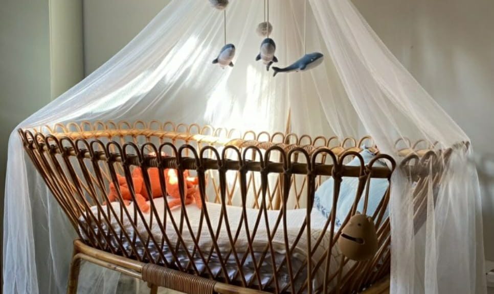 chambre avec lit bebe sur pieds avec mobile et voilage moustiquaire etagere au mur tapis carte du monde