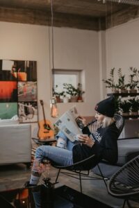 ado lisant un magazine, assise dans un fauteuil